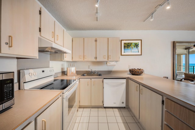 kitchen featuring track lighting, a textured ceiling, white appliances, sink, and light tile patterned floors