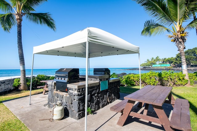 view of patio featuring a water view, grilling area, and exterior kitchen