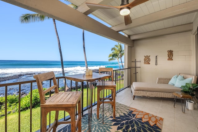 balcony with ceiling fan, a water view, and a view of the beach