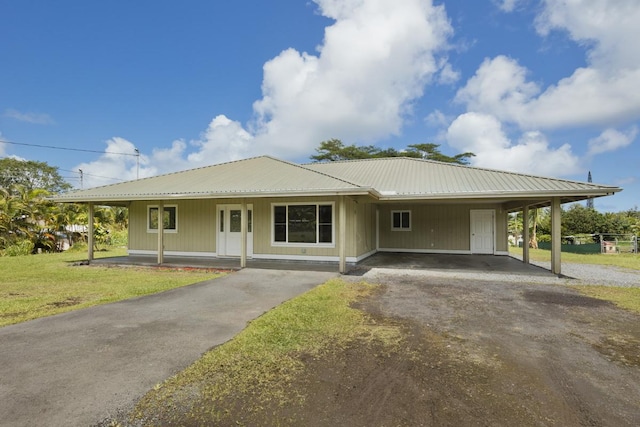 farmhouse featuring aphalt driveway, a porch, a front yard, metal roof, and a carport