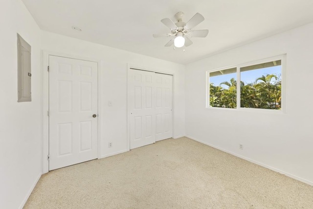 unfurnished bedroom with baseboards, light carpet, electric panel, a closet, and a ceiling fan