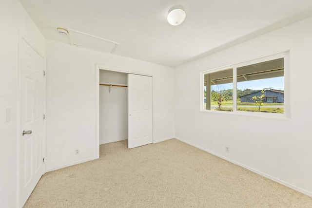 unfurnished bedroom with a closet, carpet flooring, attic access, and baseboards