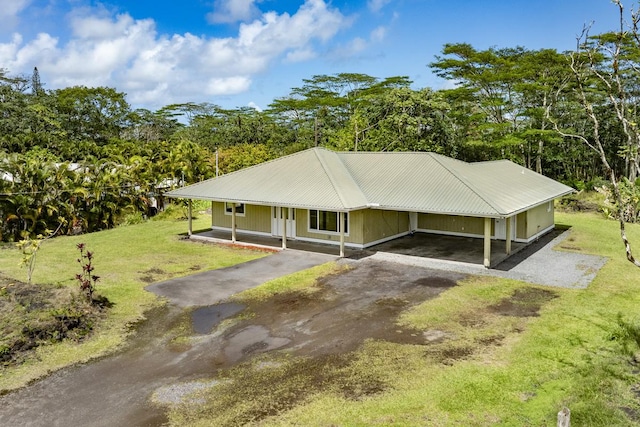 exterior space featuring driveway, covered porch, a front yard, metal roof, and a carport