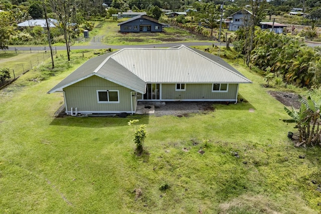 back of property featuring a lawn and metal roof