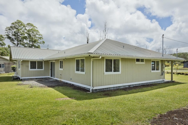 rear view of house with a lawn and metal roof