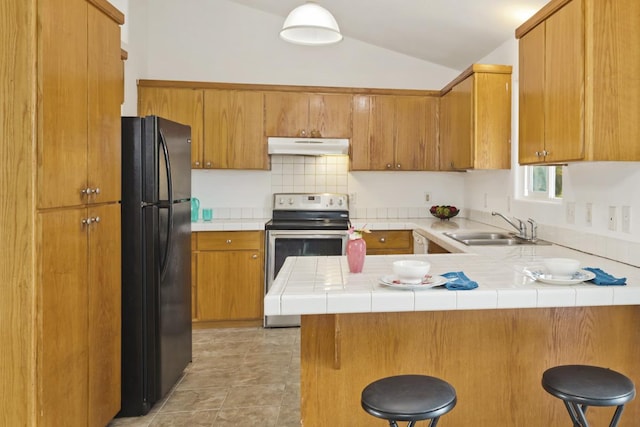 kitchen featuring a peninsula, stainless steel electric range, freestanding refrigerator, a sink, and under cabinet range hood