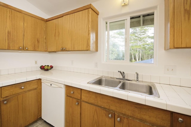 kitchen with dishwasher, light countertops, vaulted ceiling, brown cabinetry, and a sink