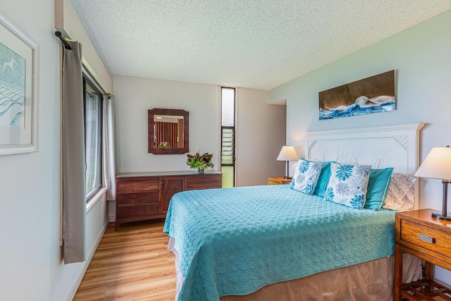 bedroom featuring a textured ceiling and light hardwood / wood-style flooring