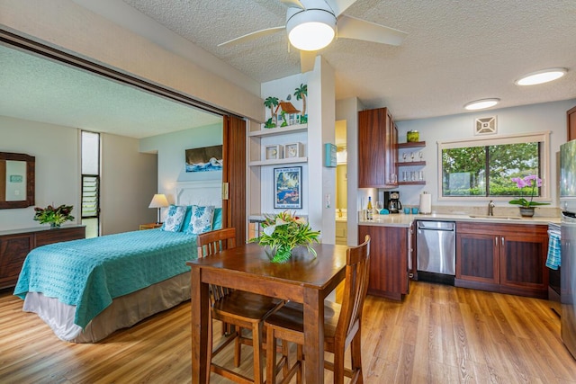 interior space featuring ceiling fan, sink, light wood-type flooring, and a textured ceiling