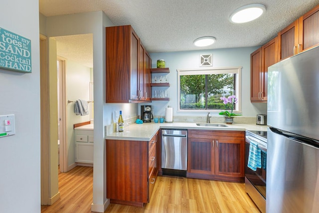 kitchen with sink, light wood-type flooring, a textured ceiling, and appliances with stainless steel finishes