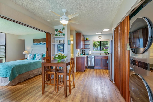 interior space with a textured ceiling, light hardwood / wood-style floors, stacked washer and dryer, and stainless steel appliances