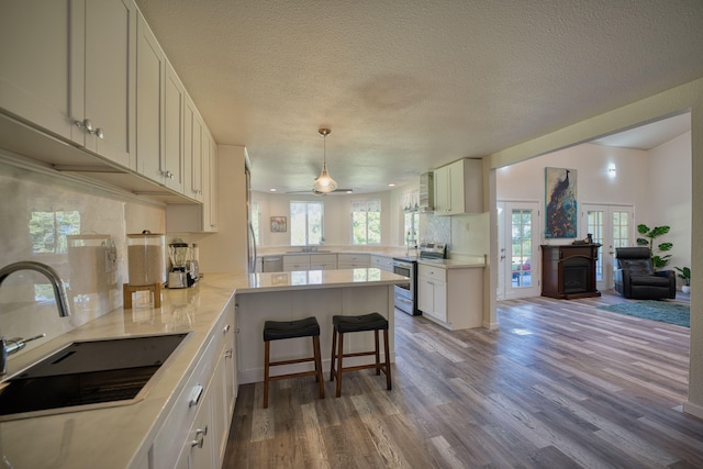 kitchen with a kitchen bar, sink, decorative light fixtures, hardwood / wood-style flooring, and stainless steel range with electric cooktop