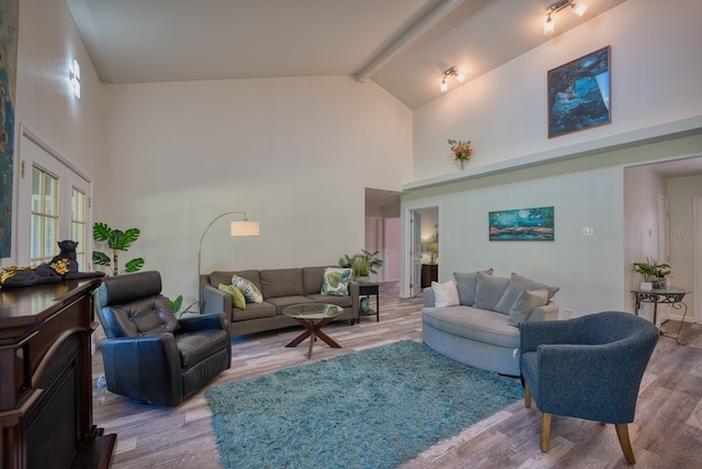 living room featuring beam ceiling, light wood-type flooring, and high vaulted ceiling