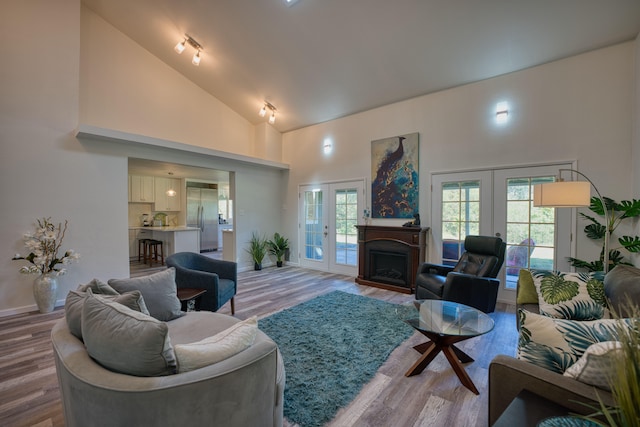 living room featuring wood-type flooring, high vaulted ceiling, and french doors