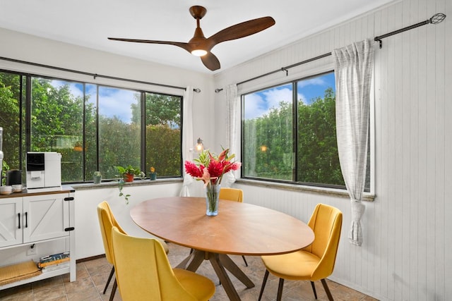 dining room with ceiling fan and wood walls