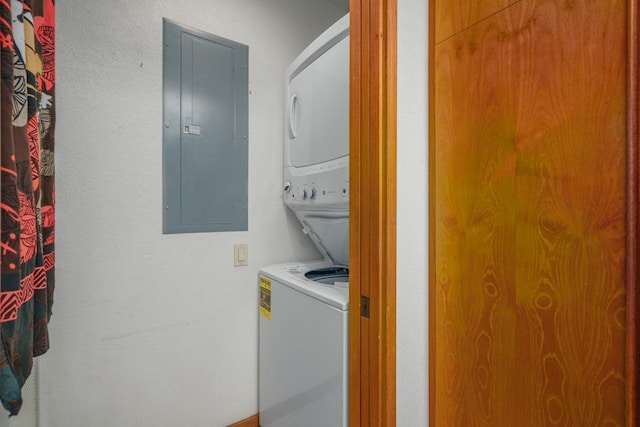 clothes washing area with electric panel and stacked washing maching and dryer