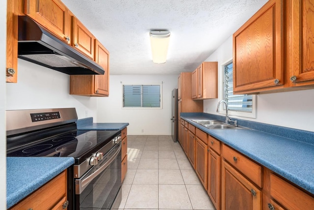 kitchen with a textured ceiling, sink, light tile patterned floors, and stainless steel appliances