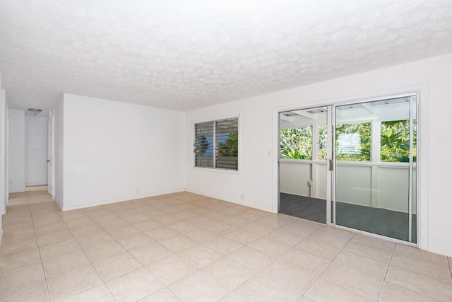 tiled empty room featuring a textured ceiling