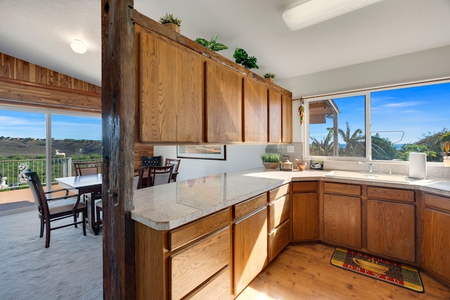 kitchen with light hardwood / wood-style floors, sink, wooden walls, and vaulted ceiling