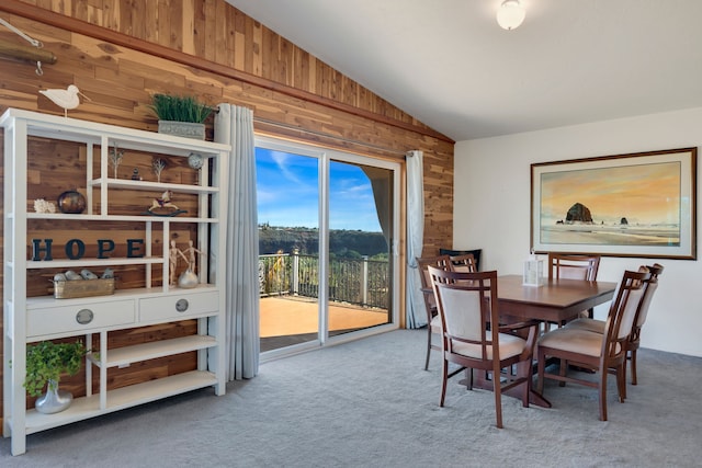 dining area featuring carpet flooring, wood walls, and lofted ceiling