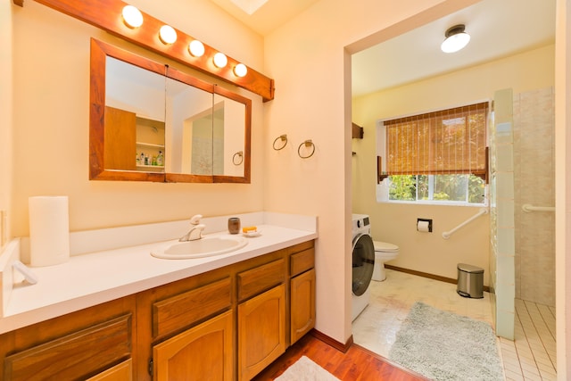 bathroom with vanity, a shower, hardwood / wood-style flooring, washer / clothes dryer, and toilet