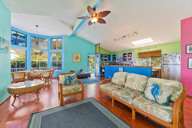 living room featuring lofted ceiling with skylight, hardwood / wood-style floors, and ceiling fan