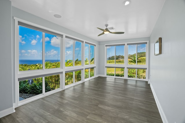 unfurnished sunroom with ceiling fan and a water view