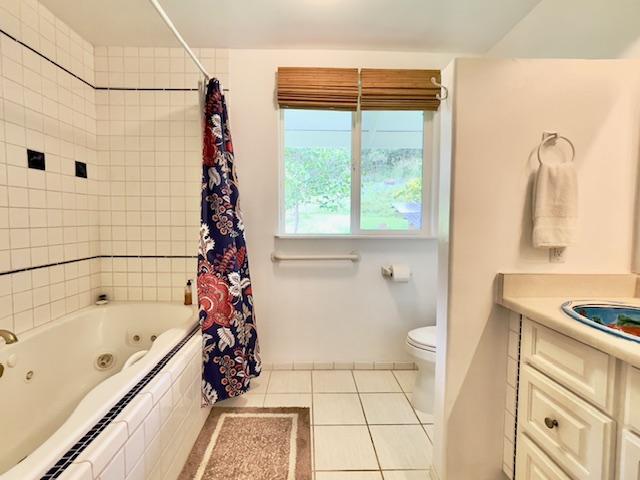 full bathroom featuring tile patterned floors, vanity, shower / bath combination with curtain, and toilet