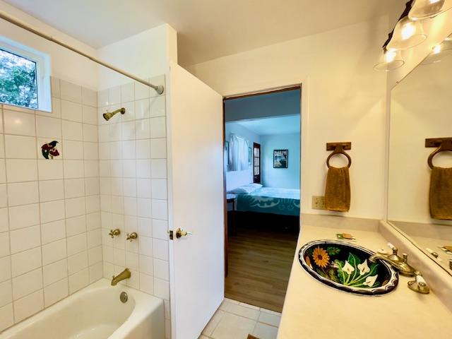 bathroom with tiled shower / bath combo and hardwood / wood-style flooring