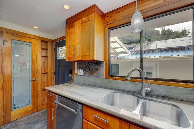 kitchen with sink, dishwasher, tasteful backsplash, light stone counters, and decorative light fixtures