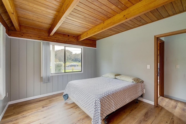 bedroom featuring beam ceiling, light hardwood / wood-style flooring, and wood ceiling