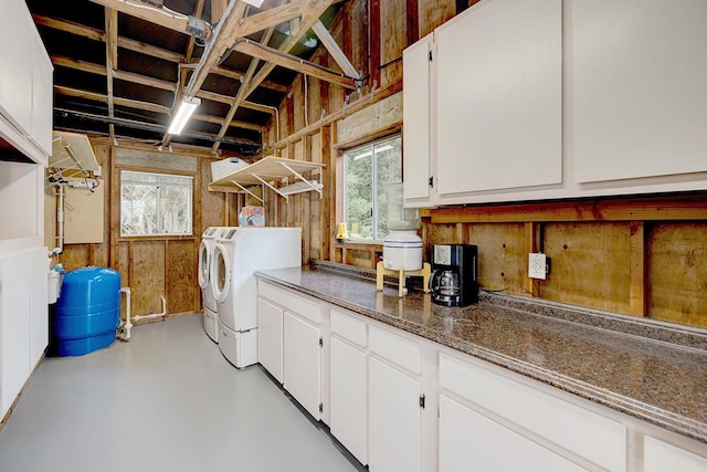 clothes washing area featuring separate washer and dryer, wood walls, and cabinets