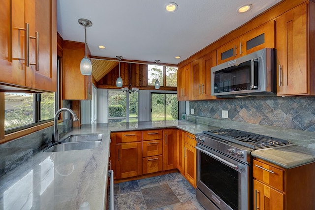 kitchen featuring decorative backsplash, light stone counters, stainless steel appliances, sink, and pendant lighting