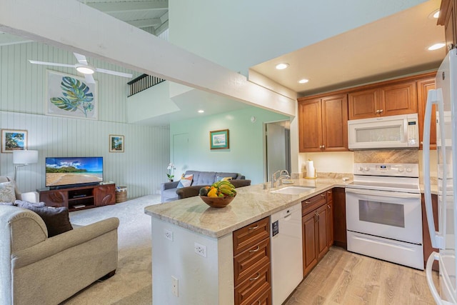 kitchen with sink, light stone counters, light hardwood / wood-style flooring, kitchen peninsula, and white appliances