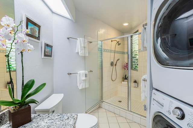 bathroom with tile patterned floors, stacked washer / drying machine, toilet, and a shower with door