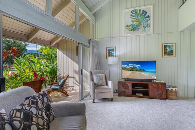 living room with carpet, beam ceiling, wood walls, and high vaulted ceiling