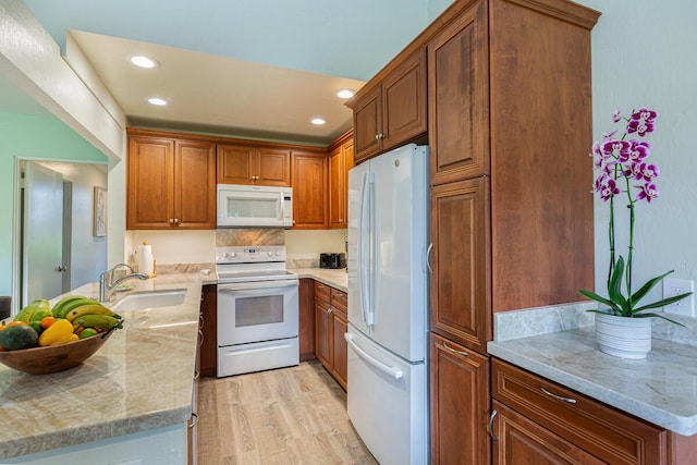 kitchen featuring light stone counters, sink, white appliances, and light hardwood / wood-style flooring