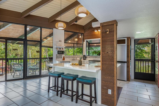 kitchen featuring a healthy amount of sunlight, a kitchen bar, and vaulted ceiling with beams