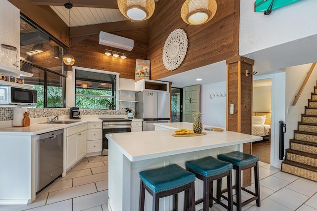 kitchen with white cabinetry, stainless steel appliances, a kitchen breakfast bar, and an AC wall unit