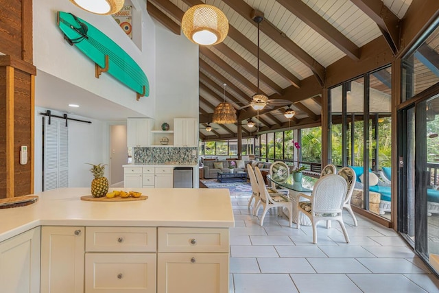 kitchen with pendant lighting, high vaulted ceiling, tasteful backsplash, beamed ceiling, and a barn door