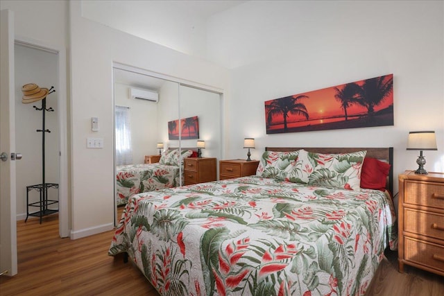 bedroom with a wall mounted AC, dark hardwood / wood-style floors, and a closet