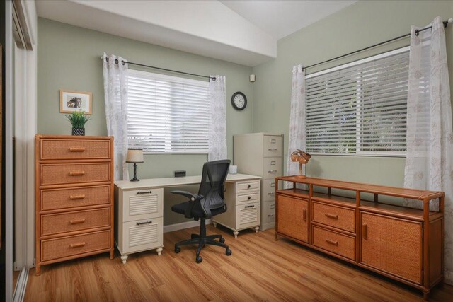 office featuring vaulted ceiling, light hardwood / wood-style flooring, and a healthy amount of sunlight