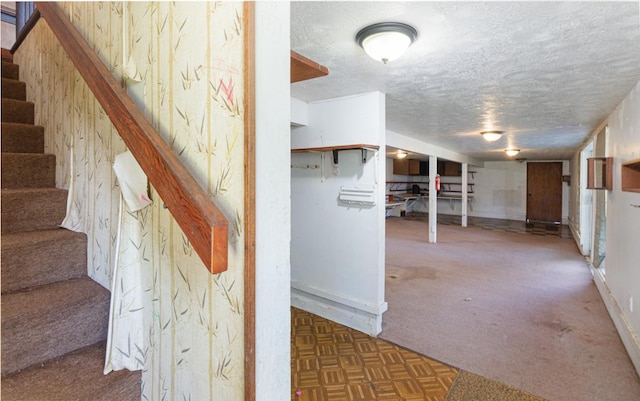 basement featuring a textured ceiling and dark colored carpet