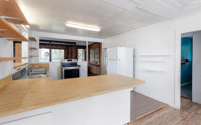 kitchen with kitchen peninsula, white fridge, hardwood / wood-style floors, stainless steel range with electric stovetop, and sink