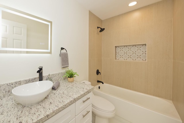 full bathroom featuring vanity, tiled shower / bath combo, and toilet