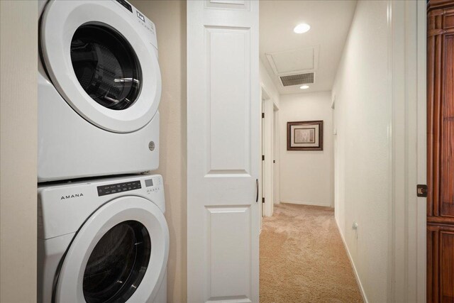 laundry area featuring stacked washer and dryer and light carpet