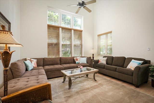 living room featuring ceiling fan, light hardwood / wood-style floors, and a high ceiling