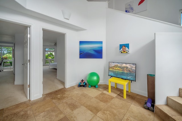 exercise area with ceiling fan, light colored carpet, and a wealth of natural light