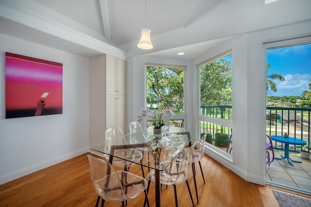 dining space featuring lofted ceiling with beams and light hardwood / wood-style flooring