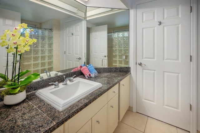 bathroom featuring tile patterned flooring, vanity, and a shower